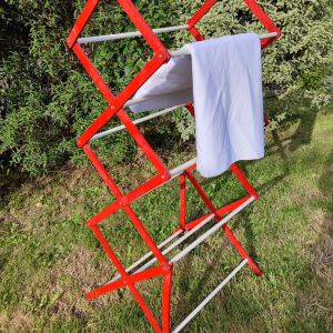 Etendoir à linge pliant "Hector" en latte de bois peintes en rouge et 10 tubes transversaux en pvc blanc. Facile à plié et déplié, il se pose partout et se range dans un petit coin. Style vintage.
