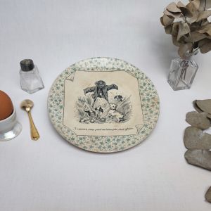 Assiette parlante "Perse" des usines de U&C Sarreguemines du début du XXème siècle. Motifs floraux verts en pourtour de l'assiette et scène de vie en noir et blanc représentants 3 chiens dans un champs de blé aboyant sur un épouvantail - A vaincre sans péril on triomphe sans gloire - Quelle leçon de morale!!!  REMARQUES : le blancheur de la faïence à jaunie avec le temps. On peut voir un tout petit éclat dans le bas de l'assiette.