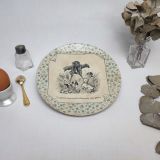 Assiette parlante "Perse" des usines de U&C Sarreguemines du début du XXème siècle. Motifs floraux verts en pourtour de l'assiette et scène de vie en noir et blanc représentants 3 chiens dans un champs de blé aboyant sur un épouvantail - A vaincre sans péril on triomphe sans gloire - Quelle leçon de morale!!!  REMARQUES : le blancheur de la faïence à jaunie avec le temps. On peut voir un tout petit éclat dans le bas de l'assiette.