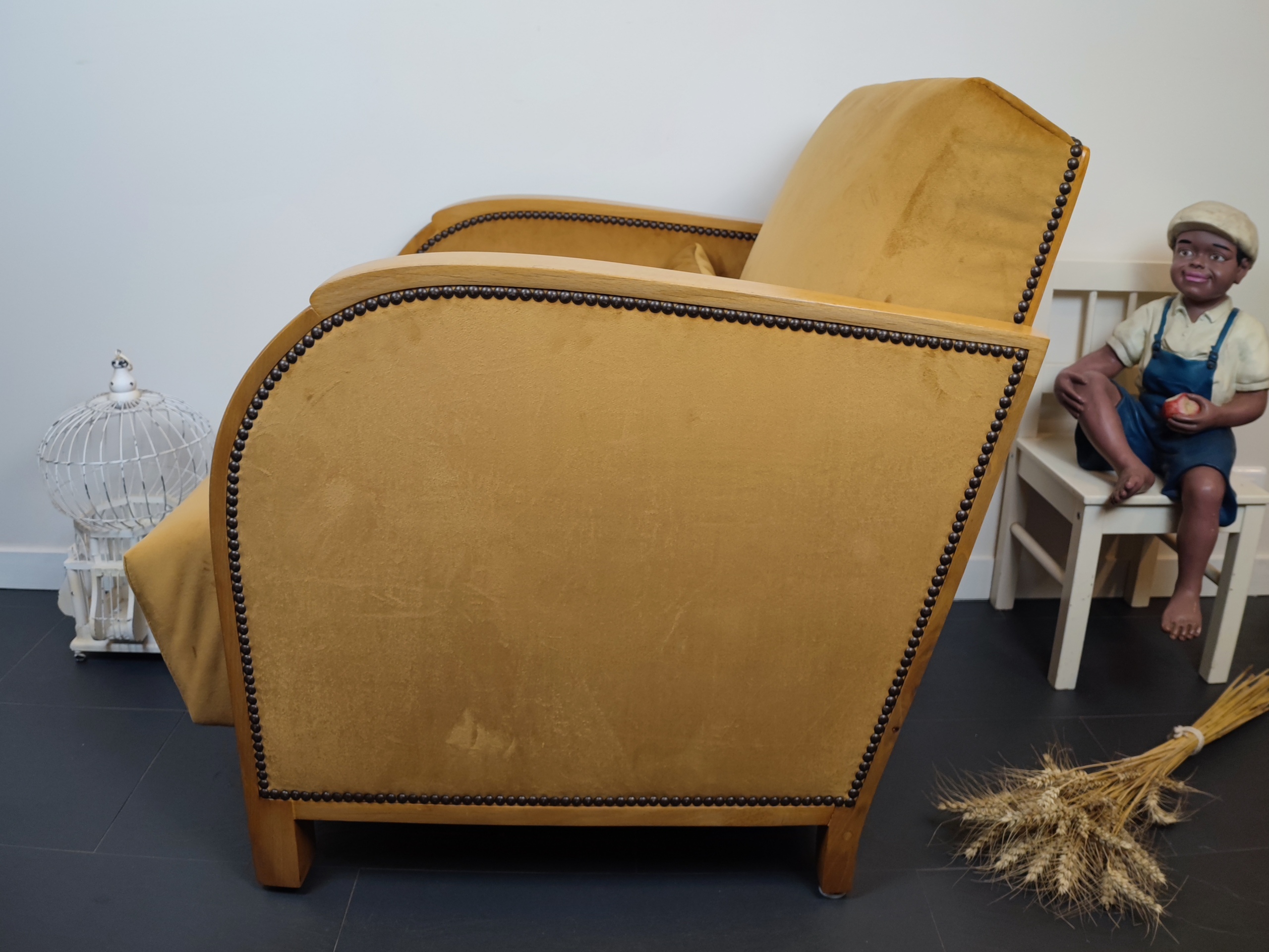 Entre lignes géométriques et chaleur du bois, André(e) incarne toute l’élégance du style Art déco. Entièrement rénové, ce fauteuil des années 1920 retrouve son éclat d’origine tout en adoptant une touche contemporaine. La structure en hêtre massif a été soigneusement poncée, traitée et éclaircie avant d’être protégée par un verni à la teinte chêne doré satiné, pour s'accorder au mieux aux fauteuils existants des clients. L’assise et le dossier ont été refaits selon les techniques traditionnelles et recouverts d’un velours miel profond, doux et lumineux, qui met en valeur la finesse des accoudoirs galbés et les détails d’époque. Chaque finition est le fruit d’un travail patient et exigeant : les coutures, invisibles, sont réalisées à la main, dans le respect du fauteuil et de son époque. Son dossier basculant offre un confort supplémentaire, parfait pour un moment de lecture ou de détente.