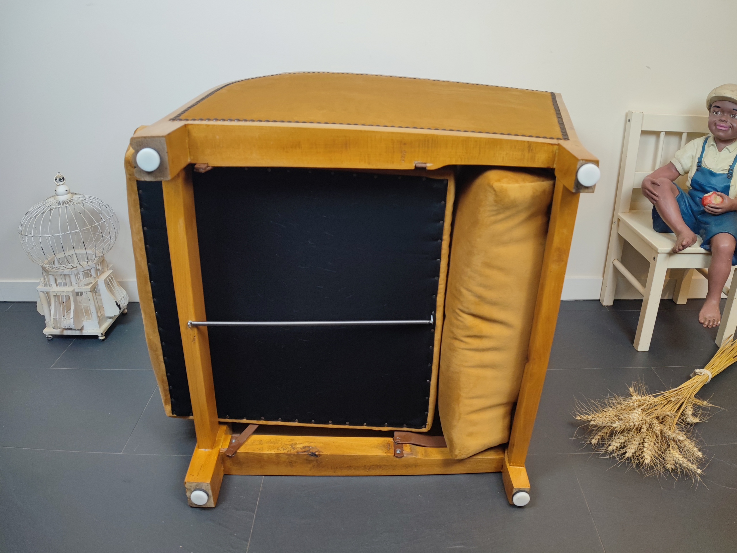 Entre lignes géométriques et chaleur du bois, André(e) incarne toute l’élégance du style Art déco. Entièrement rénové, ce fauteuil des années 1920 retrouve son éclat d’origine tout en adoptant une touche contemporaine. La structure en hêtre massif a été soigneusement poncée, traitée et éclaircie avant d’être protégée par un verni à la teinte chêne doré satiné, pour s'accorder au mieux aux fauteuils existants des clients. L’assise et le dossier ont été refaits selon les techniques traditionnelles et recouverts d’un velours miel profond, doux et lumineux, qui met en valeur la finesse des accoudoirs galbés et les détails d’époque. Chaque finition est le fruit d’un travail patient et exigeant : les coutures, invisibles, sont réalisées à la main, dans le respect du fauteuil et de son époque. Son dossier basculant offre un confort supplémentaire, parfait pour un moment de lecture ou de détente.