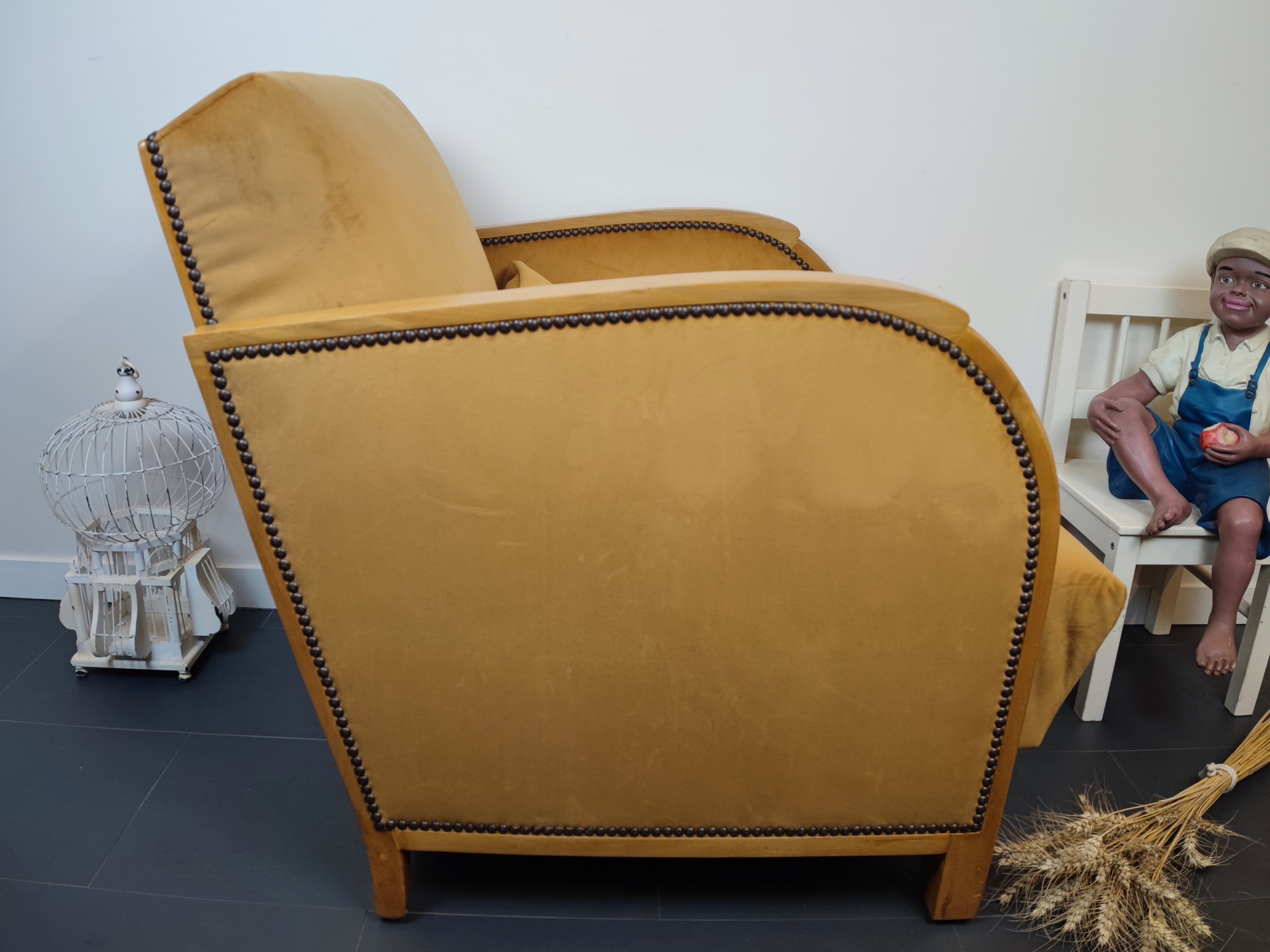 Entre lignes géométriques et chaleur du bois, André(e) incarne toute l’élégance du style Art déco. Entièrement rénové, ce fauteuil des années 1920 retrouve son éclat d’origine tout en adoptant une touche contemporaine. La structure en hêtre massif a été soigneusement poncée, traitée et éclaircie avant d’être protégée par un verni à la teinte chêne doré satiné, pour s'accorder au mieux aux fauteuils existants des clients. L’assise et le dossier ont été refaits selon les techniques traditionnelles et recouverts d’un velours miel profond, doux et lumineux, qui met en valeur la finesse des accoudoirs galbés et les détails d’époque. Chaque finition est le fruit d’un travail patient et exigeant : les coutures, invisibles, sont réalisées à la main, dans le respect du fauteuil et de son époque. Son dossier basculant offre un confort supplémentaire, parfait pour un moment de lecture ou de détente.