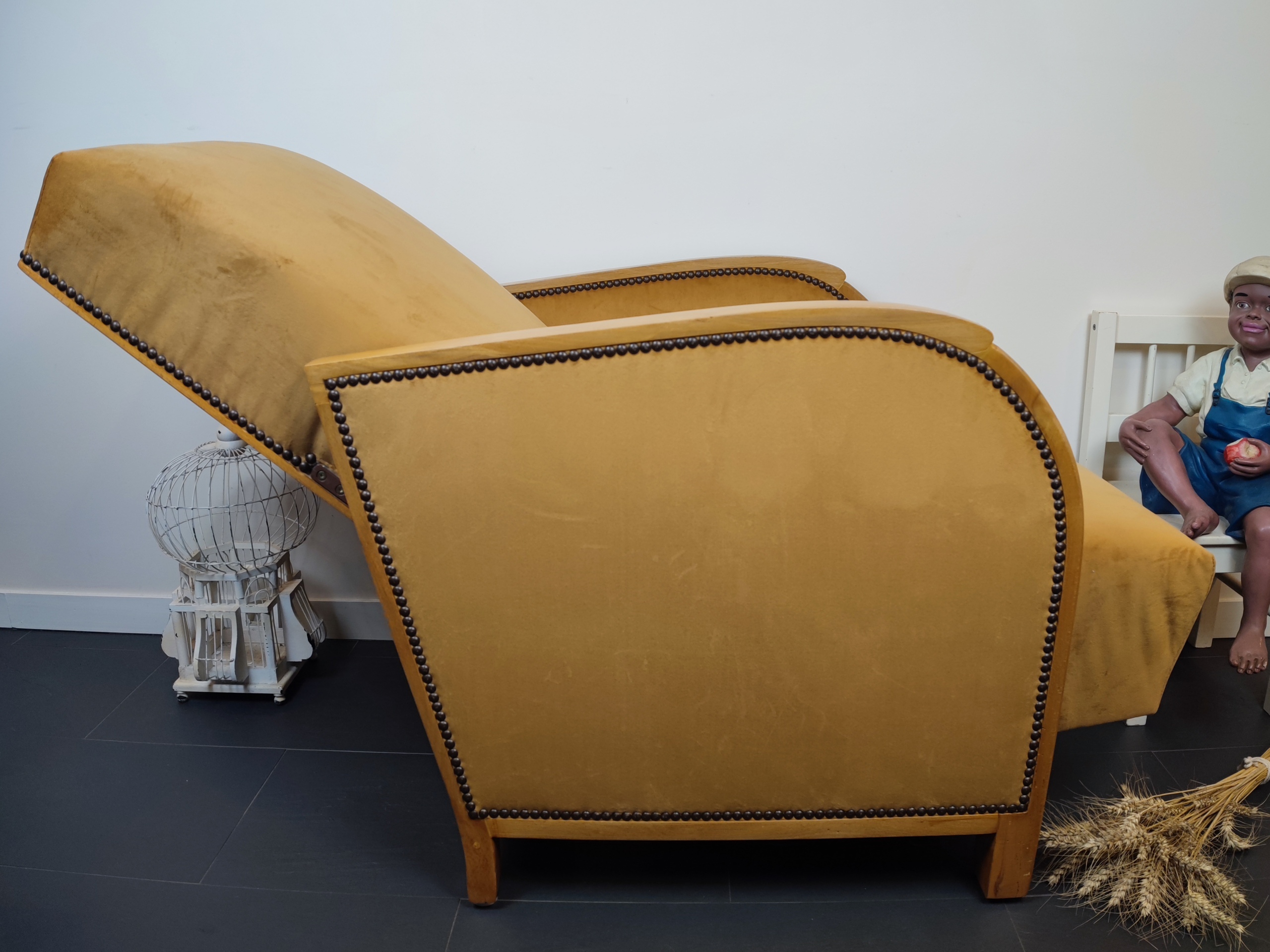 Entre lignes géométriques et chaleur du bois, André(e) incarne toute l’élégance du style Art déco. Entièrement rénové, ce fauteuil des années 1920 retrouve son éclat d’origine tout en adoptant une touche contemporaine. La structure en hêtre massif a été soigneusement poncée, traitée et éclaircie avant d’être protégée par un verni à la teinte chêne doré satiné, pour s'accorder au mieux aux fauteuils existants des clients. L’assise et le dossier ont été refaits selon les techniques traditionnelles et recouverts d’un velours miel profond, doux et lumineux, qui met en valeur la finesse des accoudoirs galbés et les détails d’époque. Chaque finition est le fruit d’un travail patient et exigeant : les coutures, invisibles, sont réalisées à la main, dans le respect du fauteuil et de son époque. Son dossier basculant offre un confort supplémentaire, parfait pour un moment de lecture ou de détente.